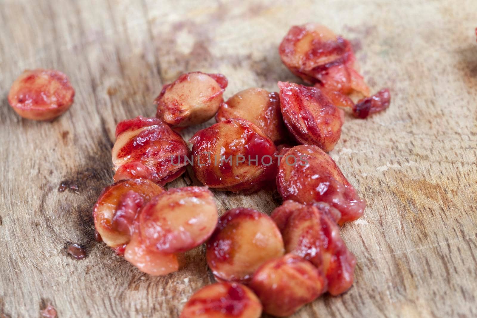 A few solid bone from a red cherry lying on a wooden board. On the bones there are the remains of the juicy pulp of mature cherry. Photo close-up of eaten berries