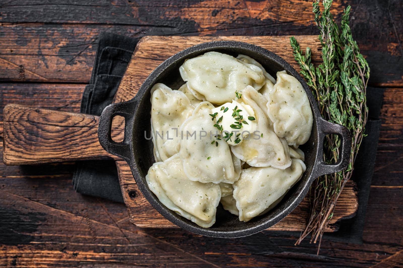 Homemade dumplings, vareniki, pierogi stuffed with potato in a pan. Dark wooden background. Top View by Composter
