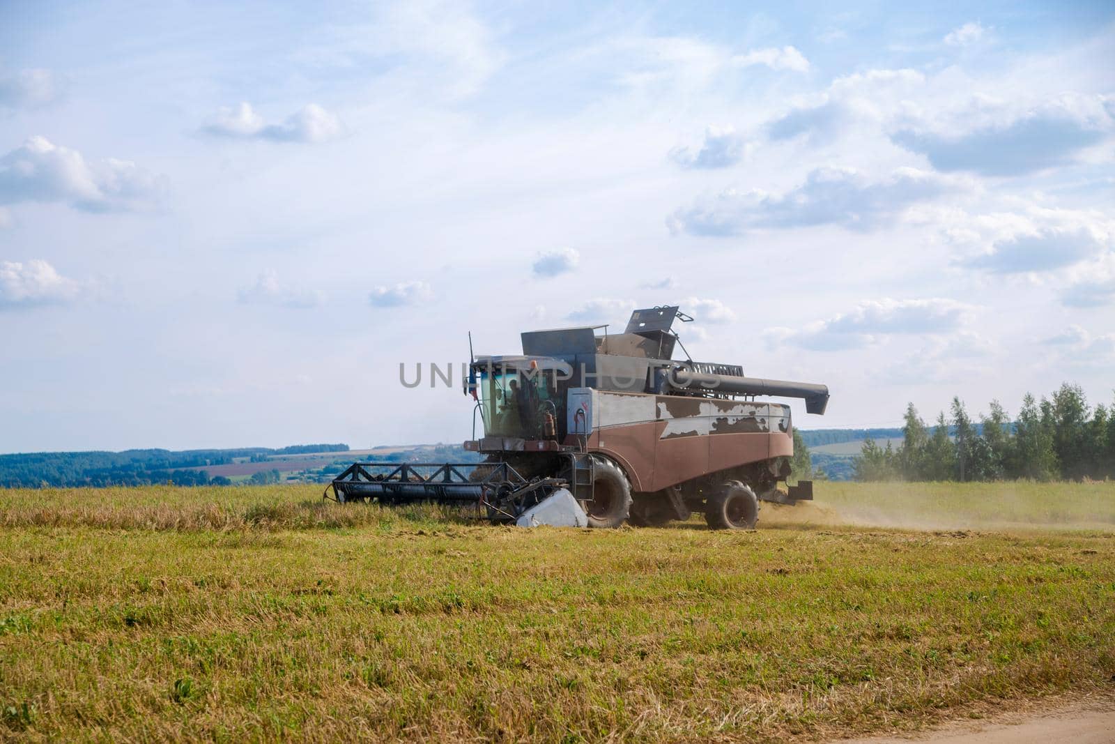 old tracktor plows the field. harvester harvests wheat from a sown agricultural field by Mariaprovector
