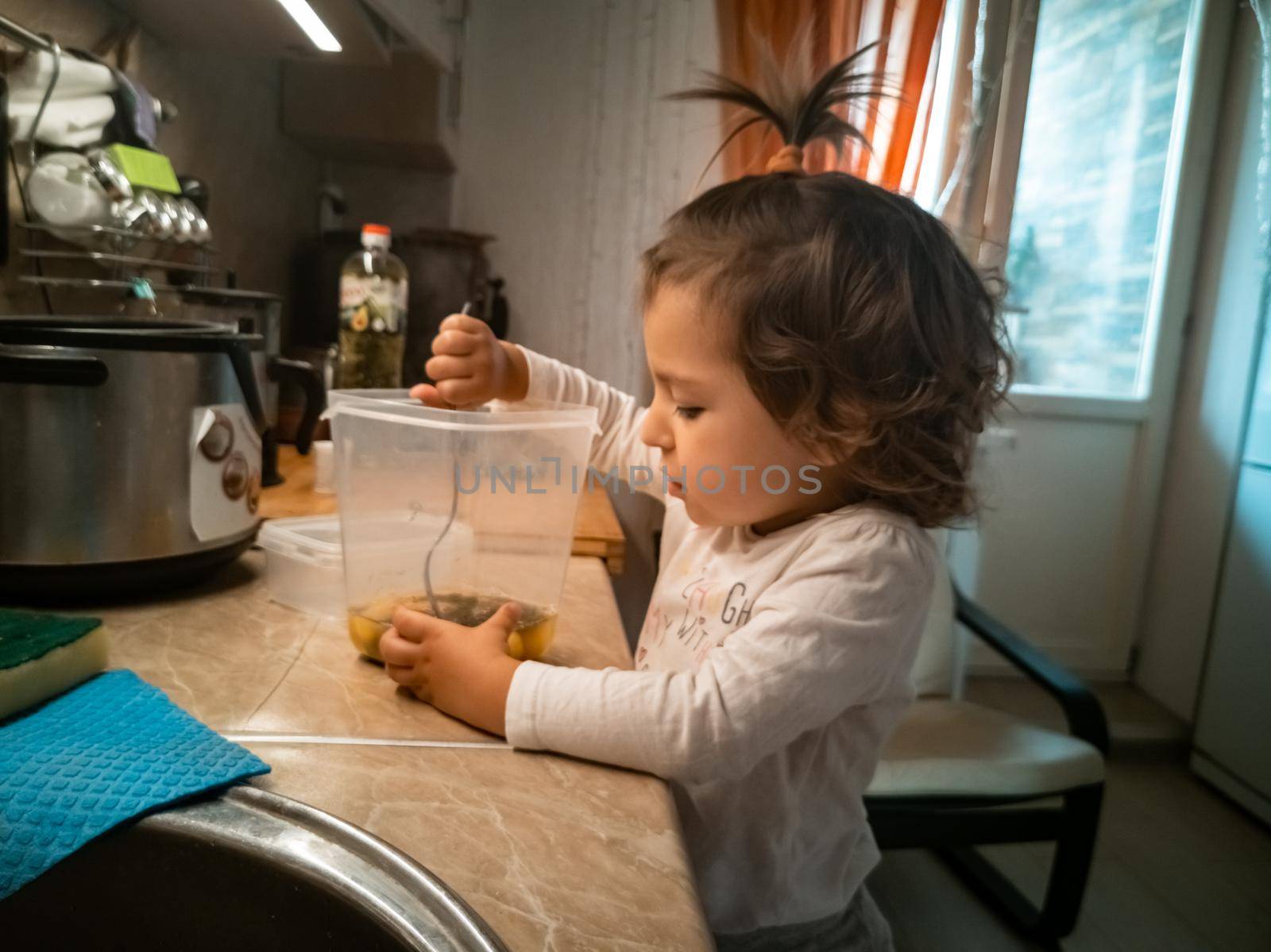 adorable little girl prepares food. Toddler in the kitchen mixing the ingredients in a bowl. real people