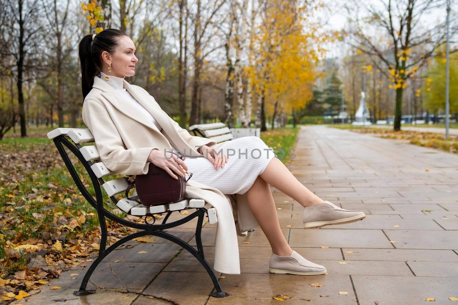 beautiful caucasian woman sitting on a bench in the park. autumn mood