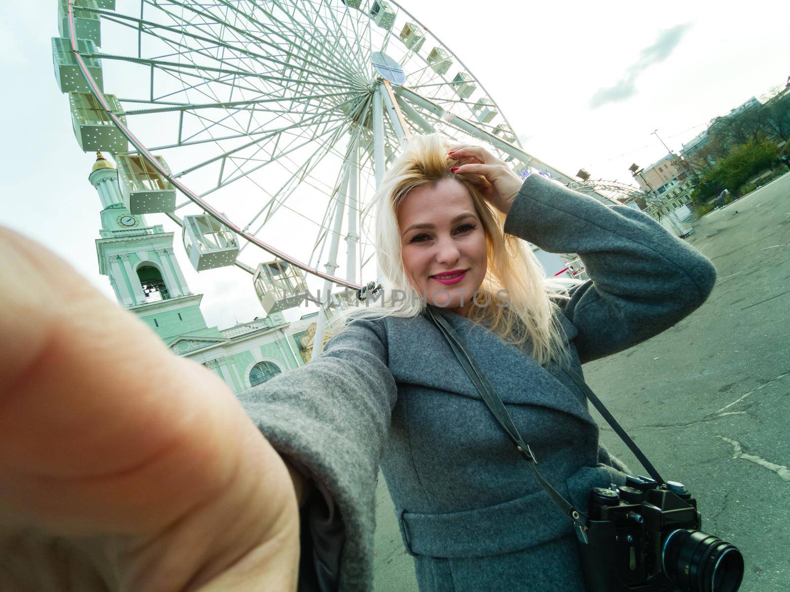 The young girl walks around the city near sights. Ferris wheel. Amusement park. autumn