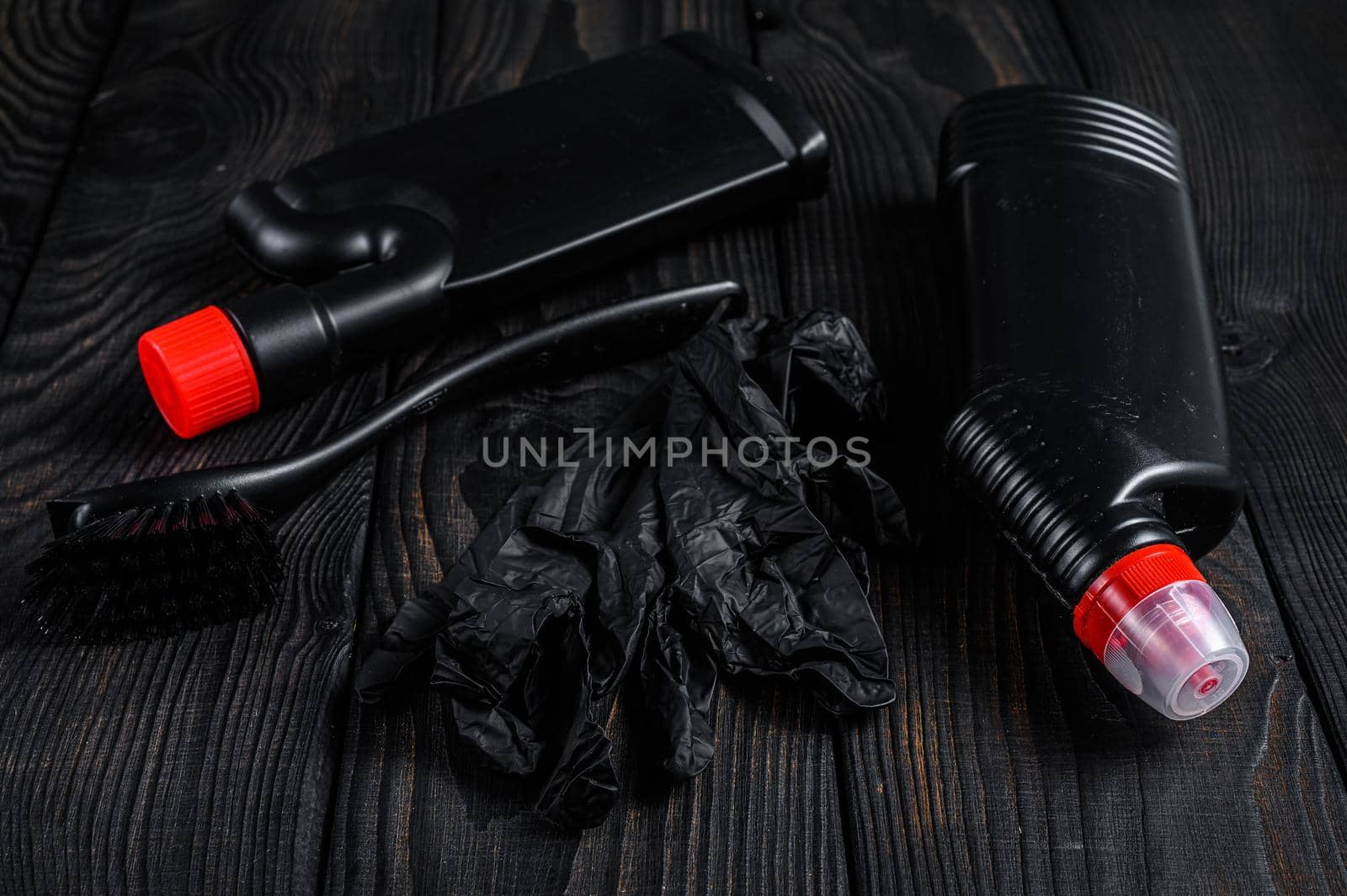 Black style Home cleaning service concept with supplies. Black wooden background. Top view.