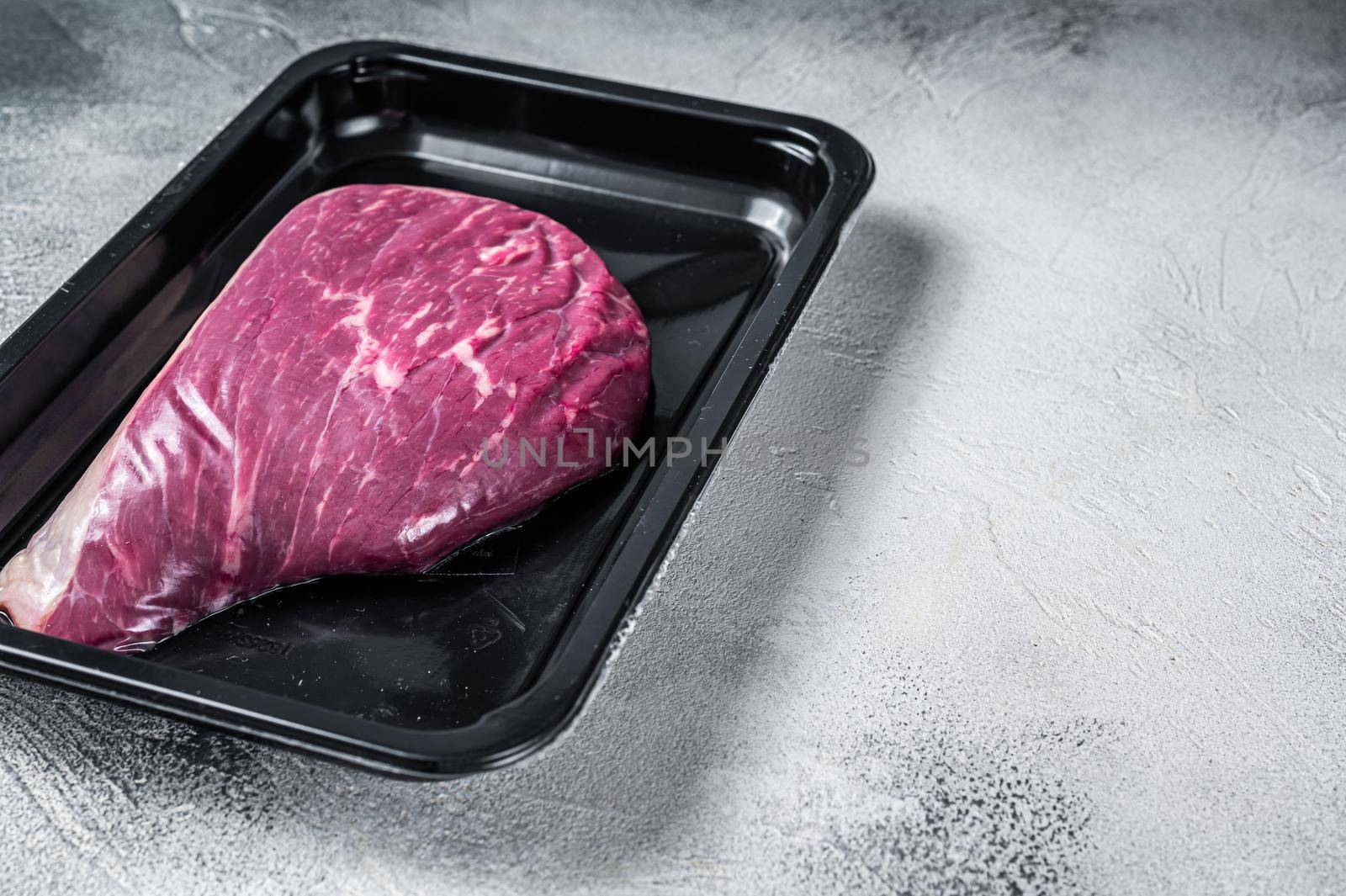 Raw cap rump steak or top sirloin beef meat steak in vacuum packaging. White background. Top view. Copy space.