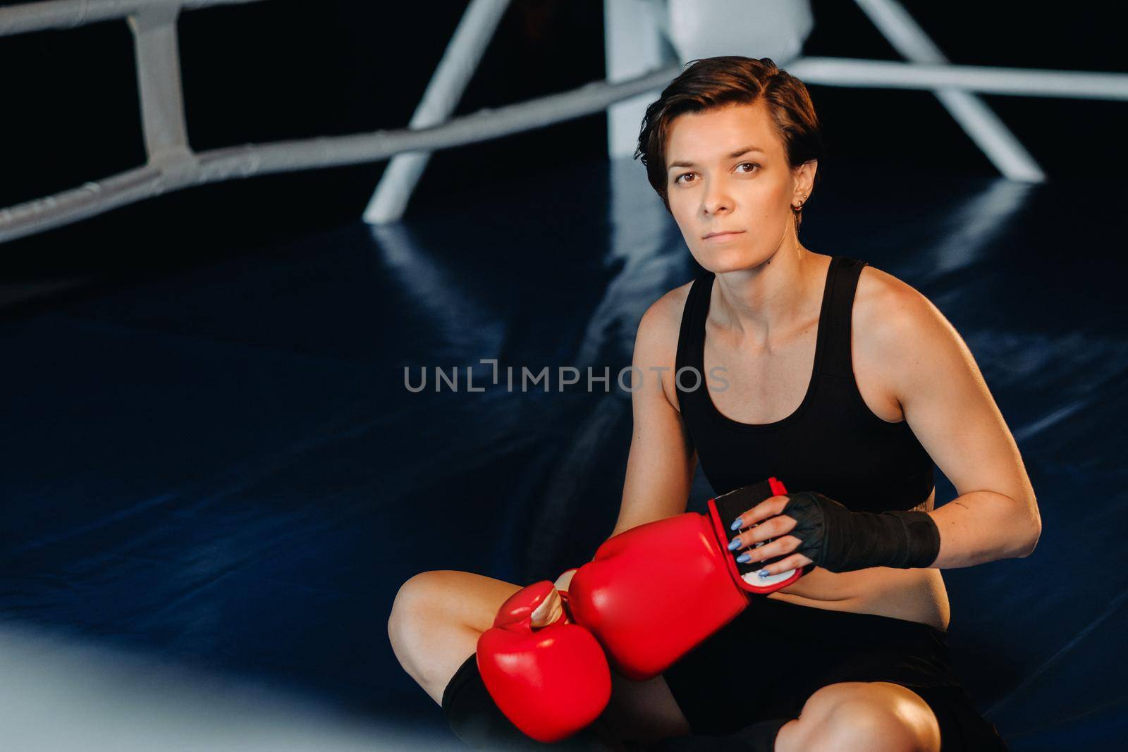 portrait of a female boxer in red gloves in the gym after training.