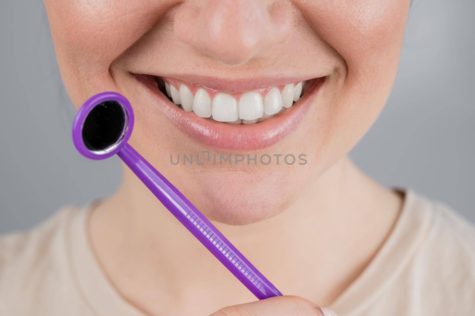Caucasian woman with snow white smile holding dentist mirror