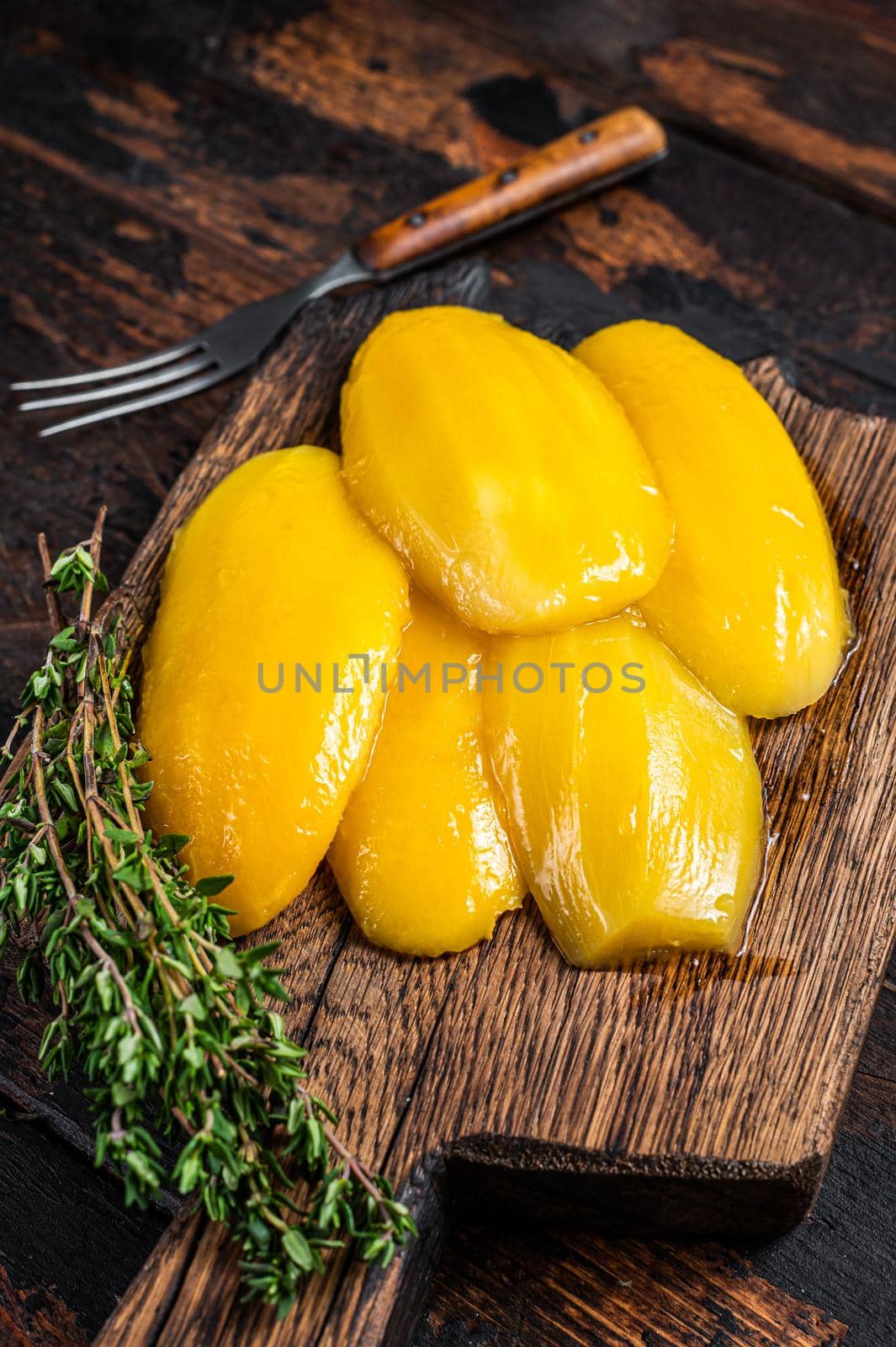 Preserve mango slices on a wooden board. Dark wooden background. Top view by Composter