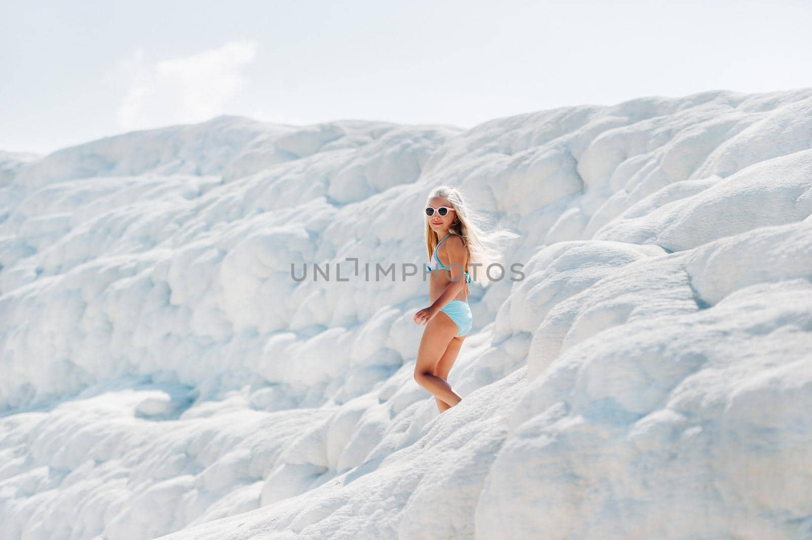 Girl in a swimsuit and sunglasses on White mountain, Sunny day, Pamukkale Turkey.