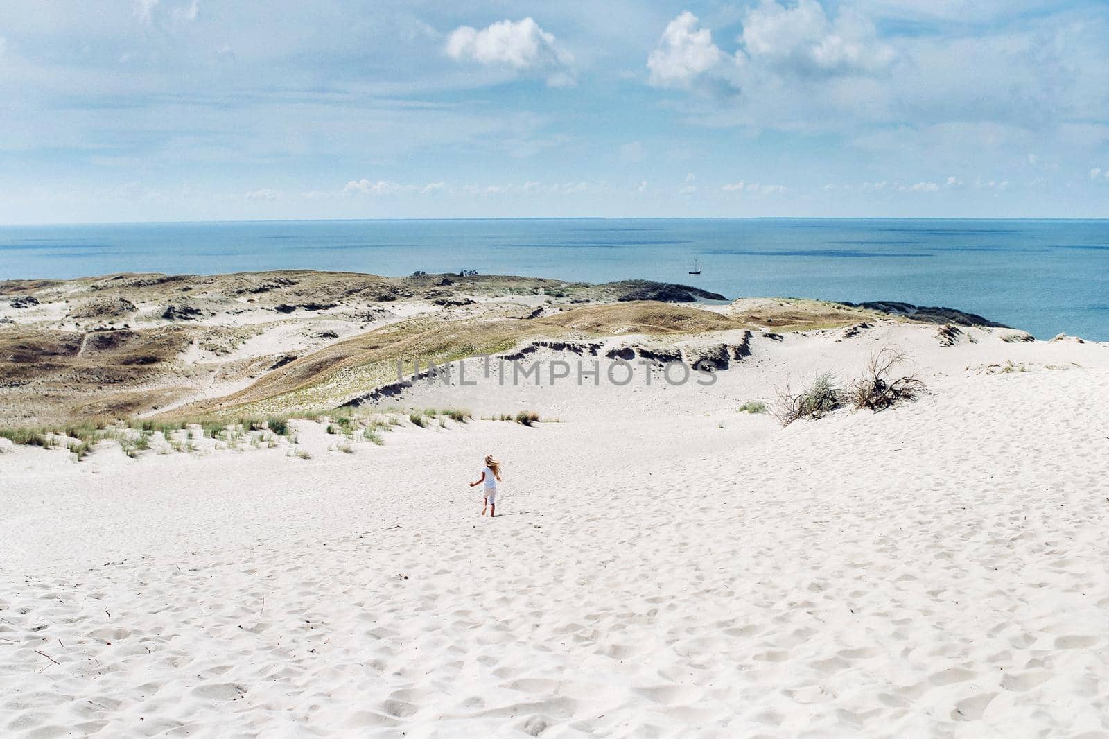 a child has fun in the sand dunes on the beach in Nida.Lithuania.