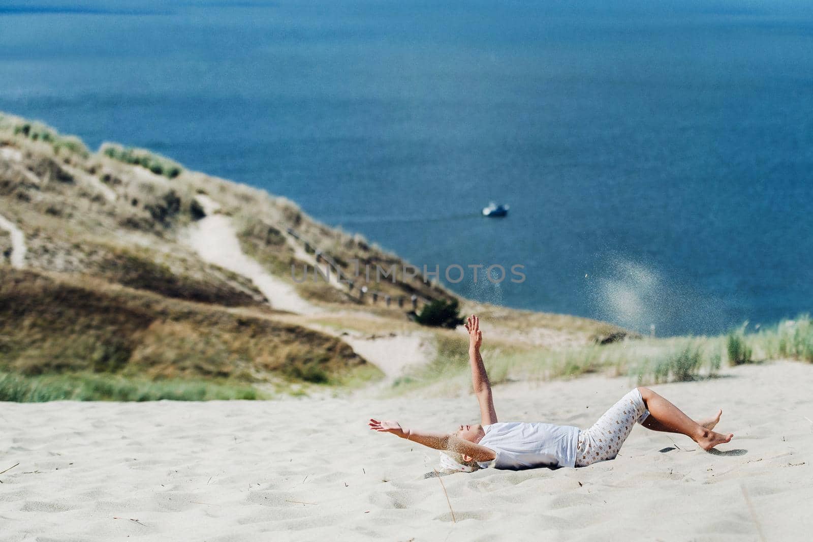 a child has fun in the sand dunes on the beach in Nida.Lithuania.