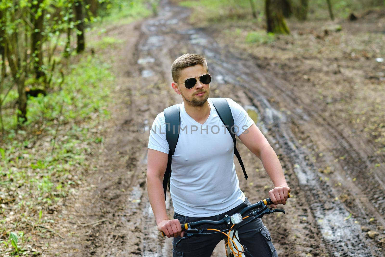 A group of cyclists with backpacks ride bicycles on a forest road enjoying nature.