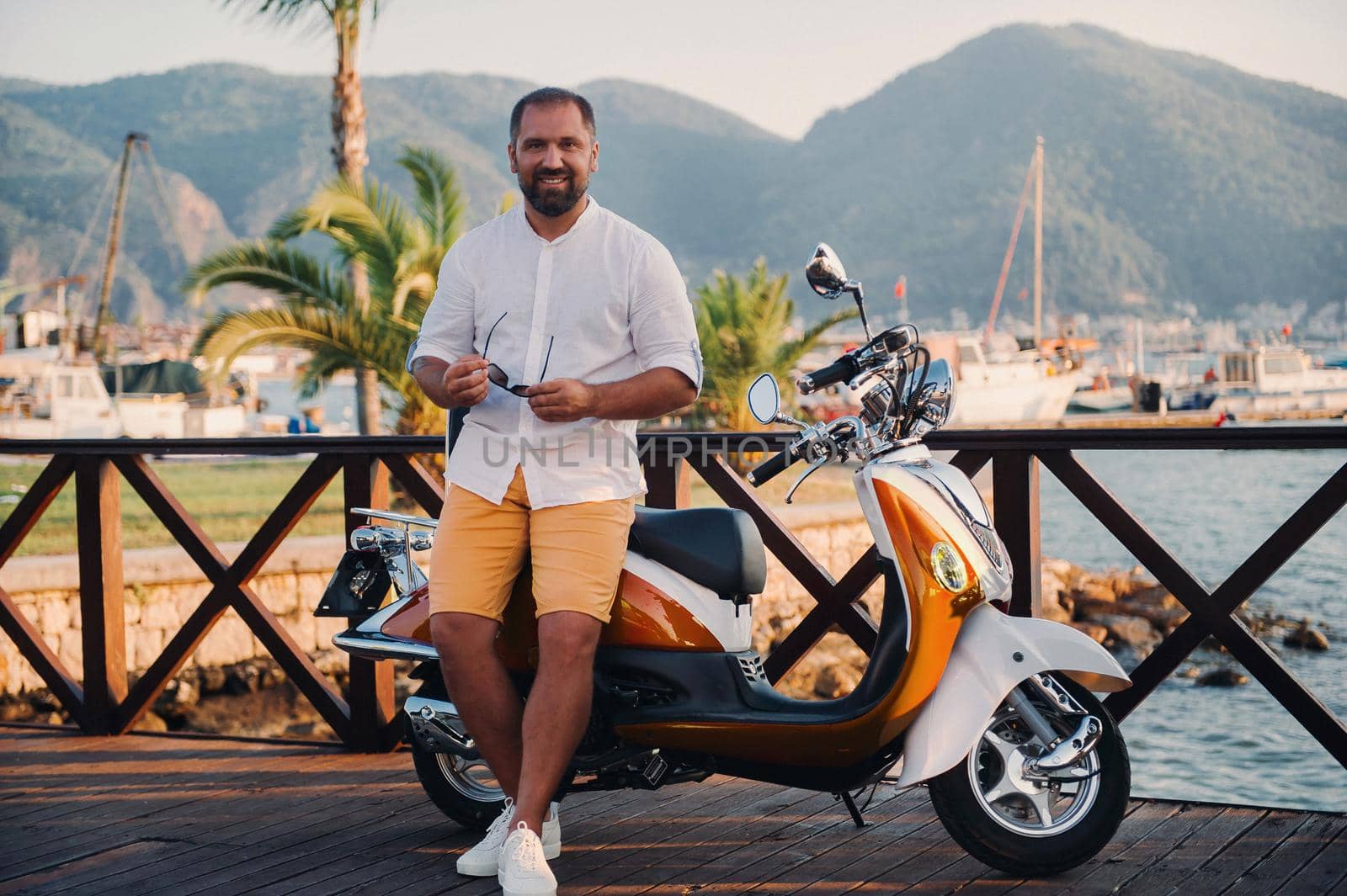 Portrait of a free happy man with scooters near the sea.Recreation, Travel on a scooter