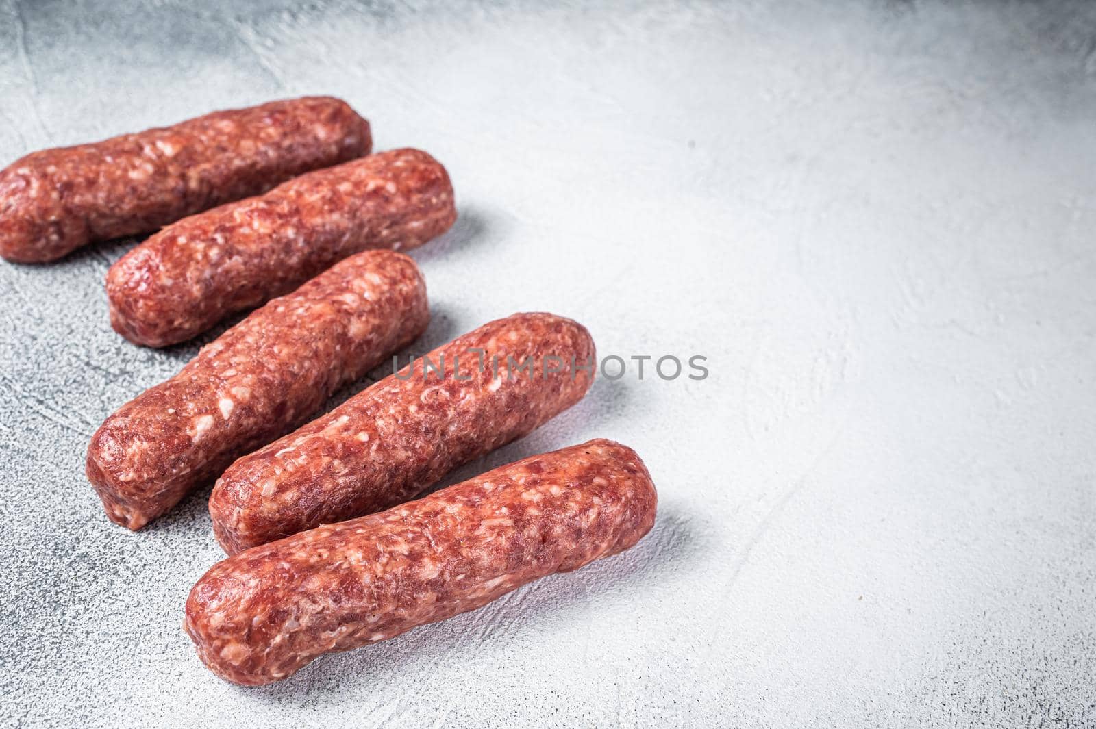 Raw beef and lamb meat kebabs sausages on a butcher table. White background. Top view. Copy space by Composter