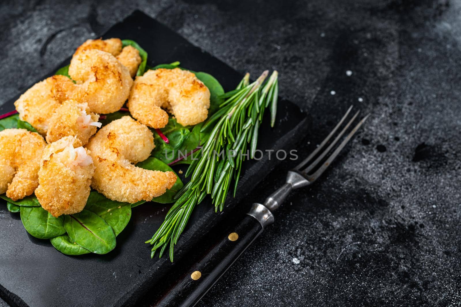 Roasted Crispy Shrimps Prawns on a marble board with green salad. Black background. Top view. Copy space by Composter