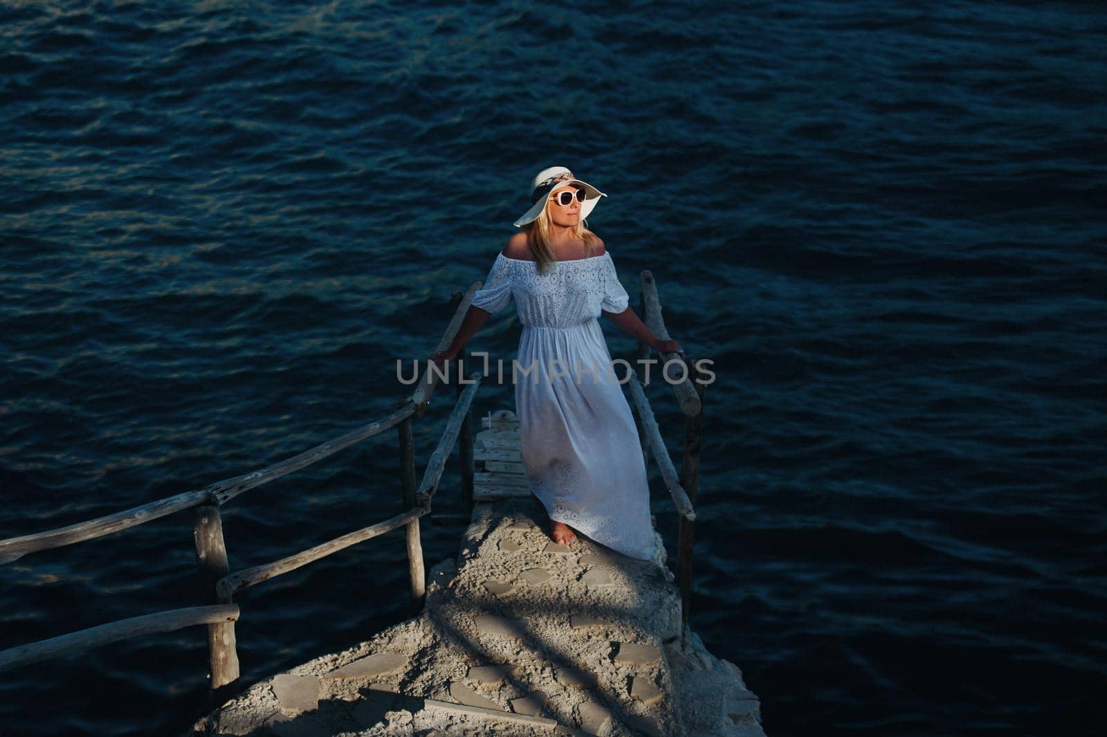 Smiling Beautiful Woman on the Beach In a Straw Hat on the island of Zakynthos.A girl in a white dress at sunset on Zakynthos island, Greece.