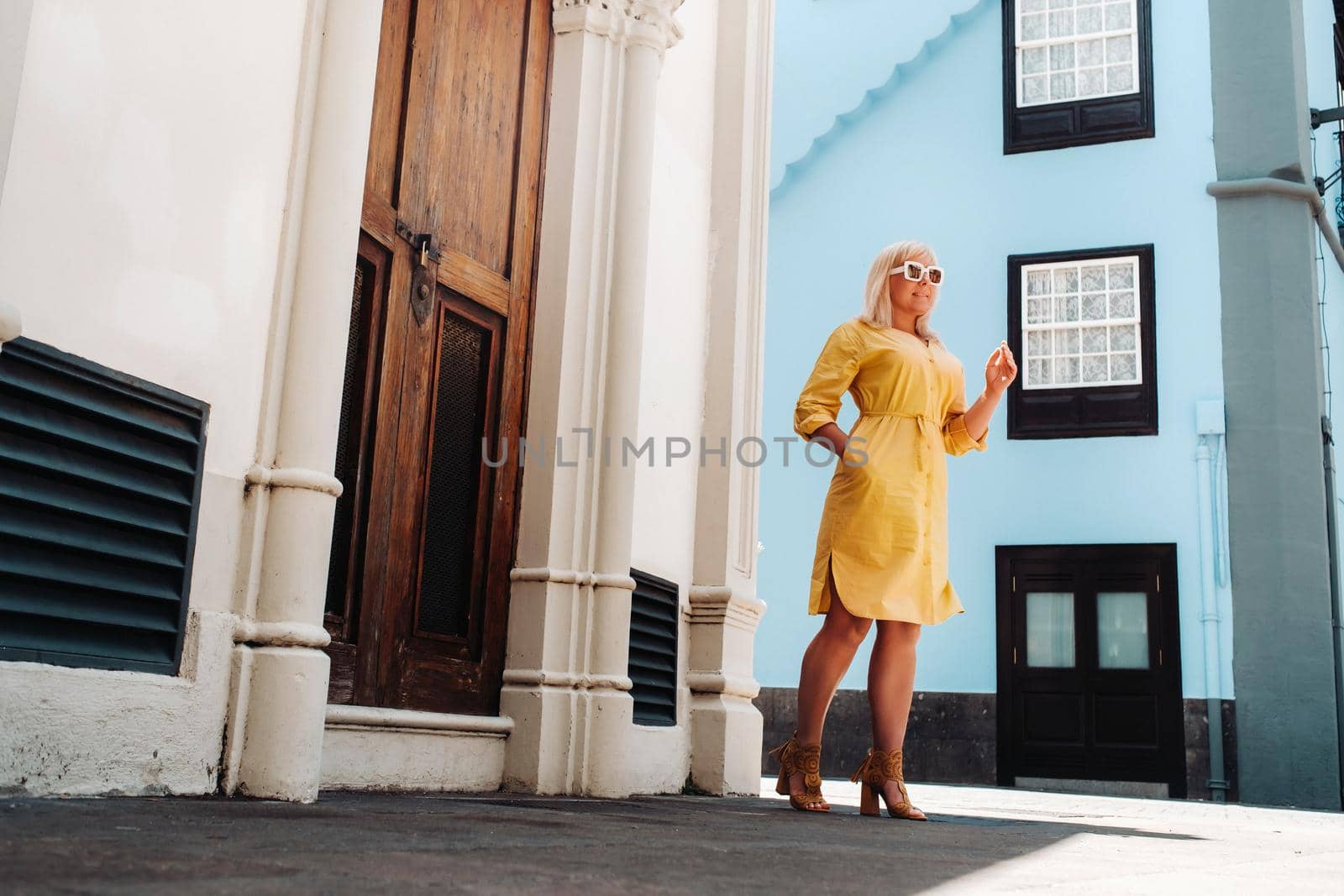 a blonde woman in a yellow summer dress stands on the street of the Old town of La Laguna on the island of Tenerife.Spain, Canary Islands.