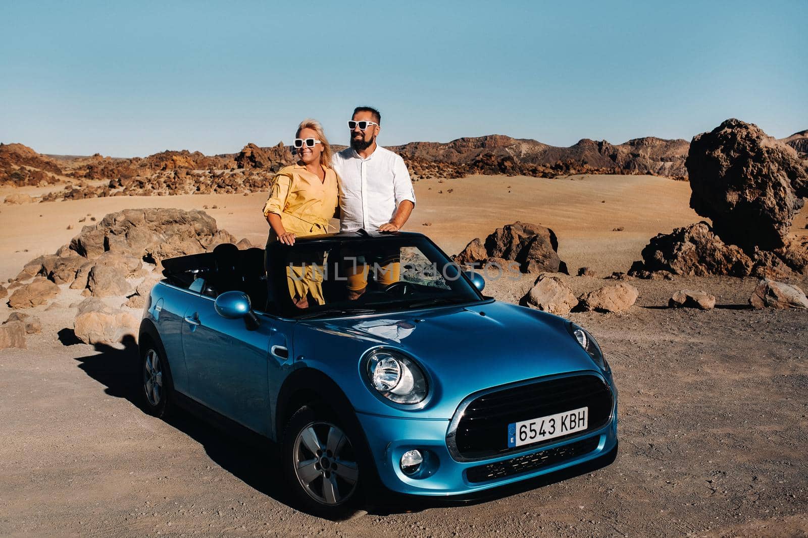 a woman and a man wearing glasses in a convertible car on a trip to the island of Tenerife. The crater of the Teide volcano, Canary Islands,Spain by Lobachad