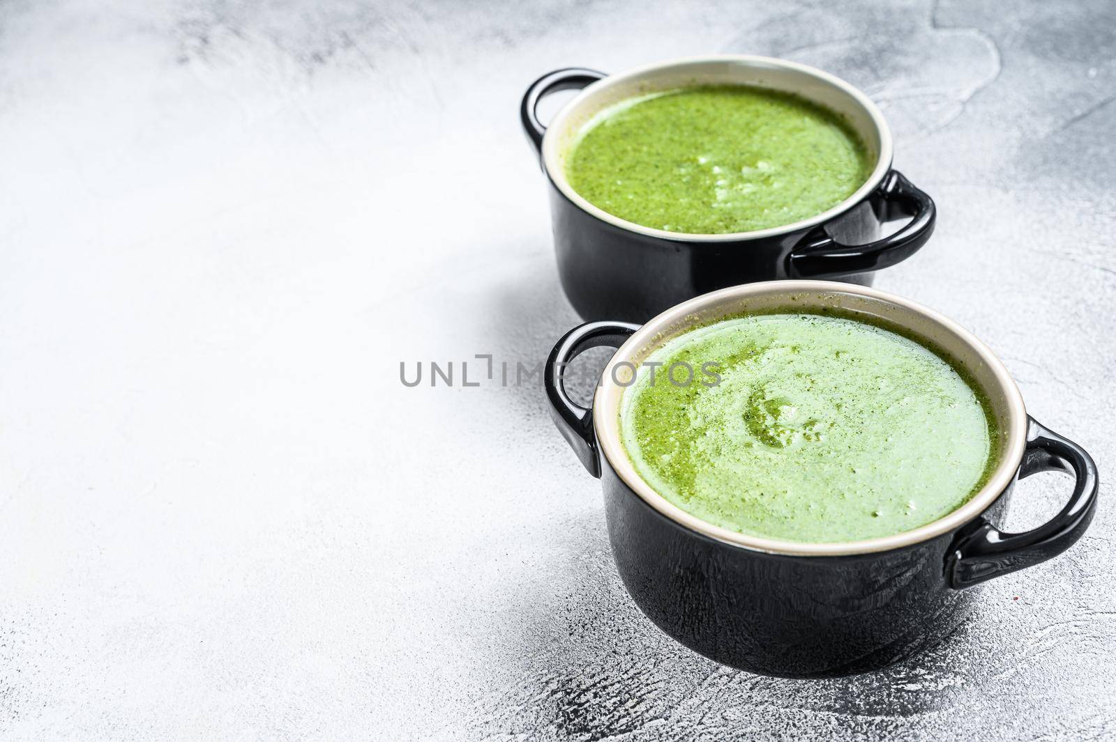 Homemade broccoli and spinach cream soup in bowl. White background. Top view. Copy space by Composter