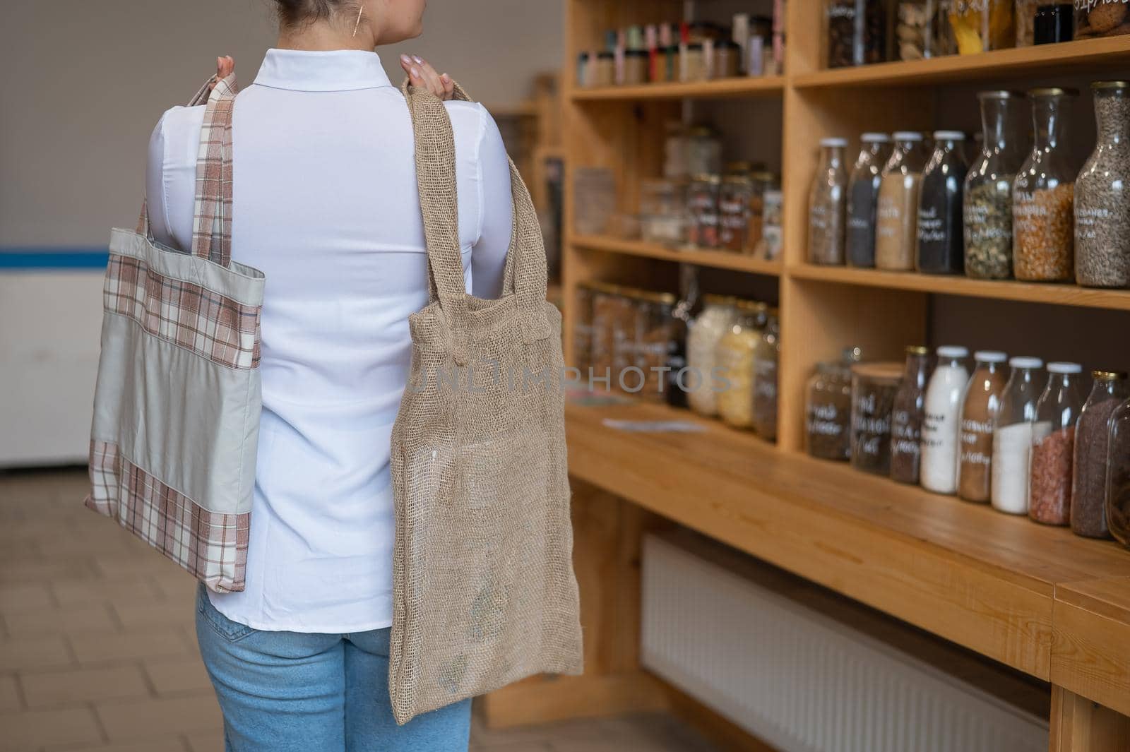 Woman choosing cotton bag at eco-friendly store.