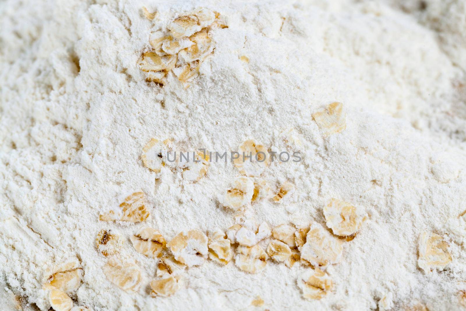 white wheat flour with oat flakes, close-up photo on wooden surface