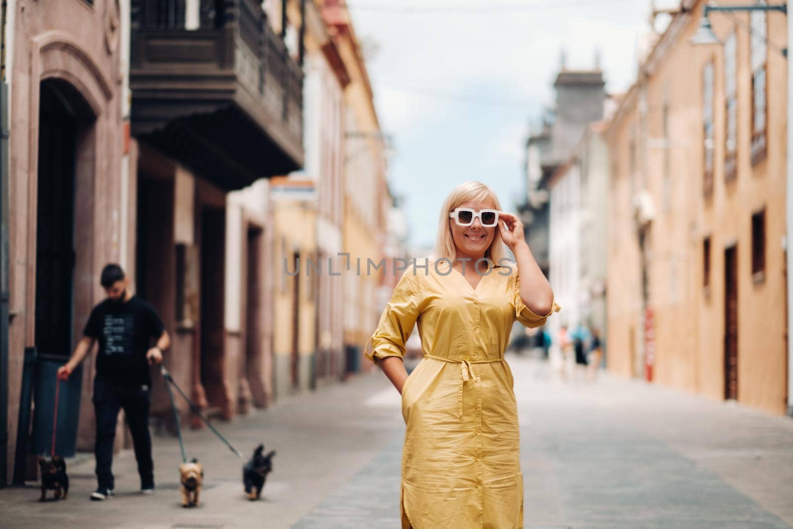 a blonde woman in a yellow summer dress stands on the street of the Old town of La Laguna on the island of Tenerife.Spain, Canary Islands.