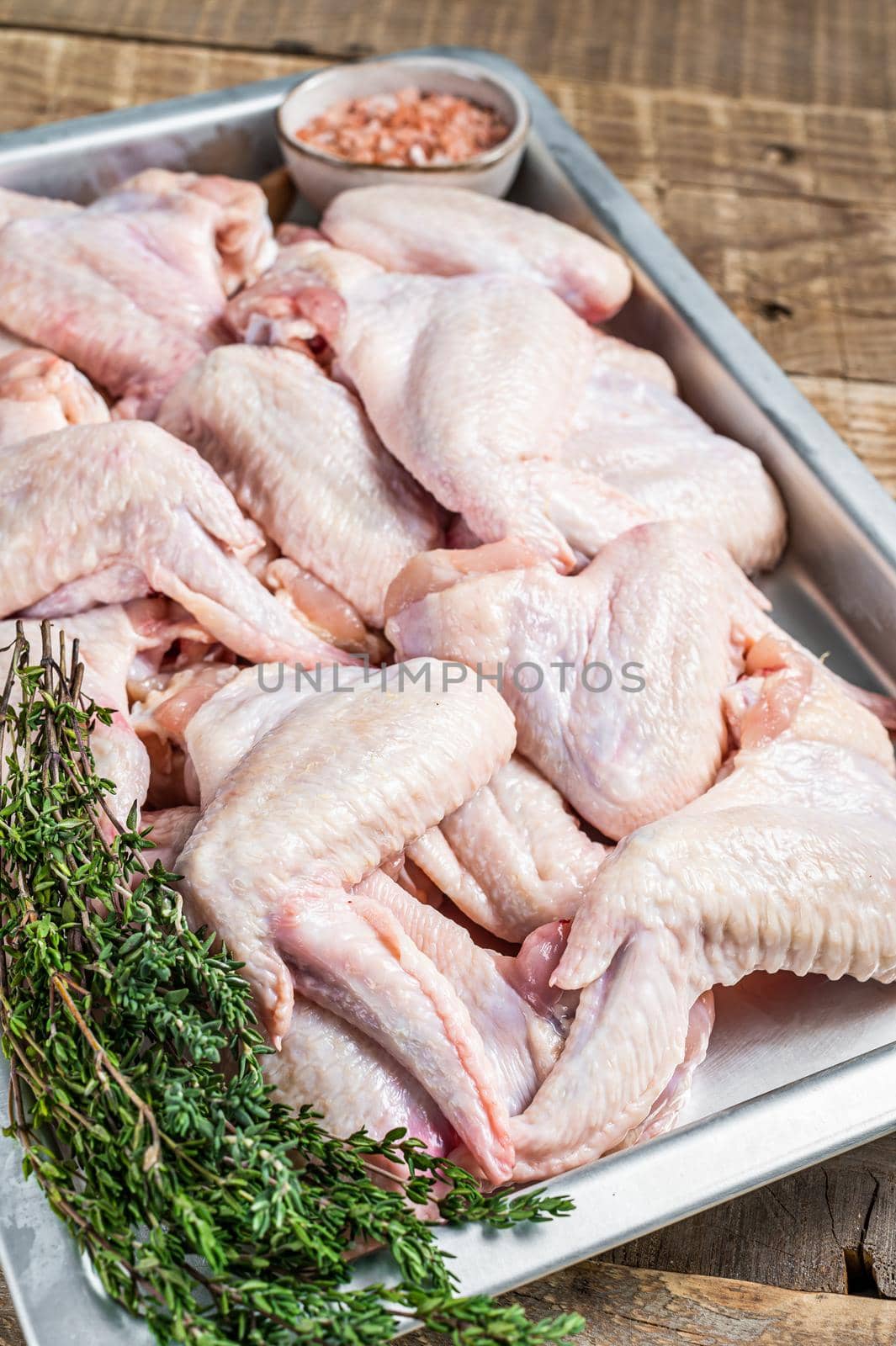 Raw chicken wings Poultry meat ready for cooking with herbs. Wooden background. Top view.