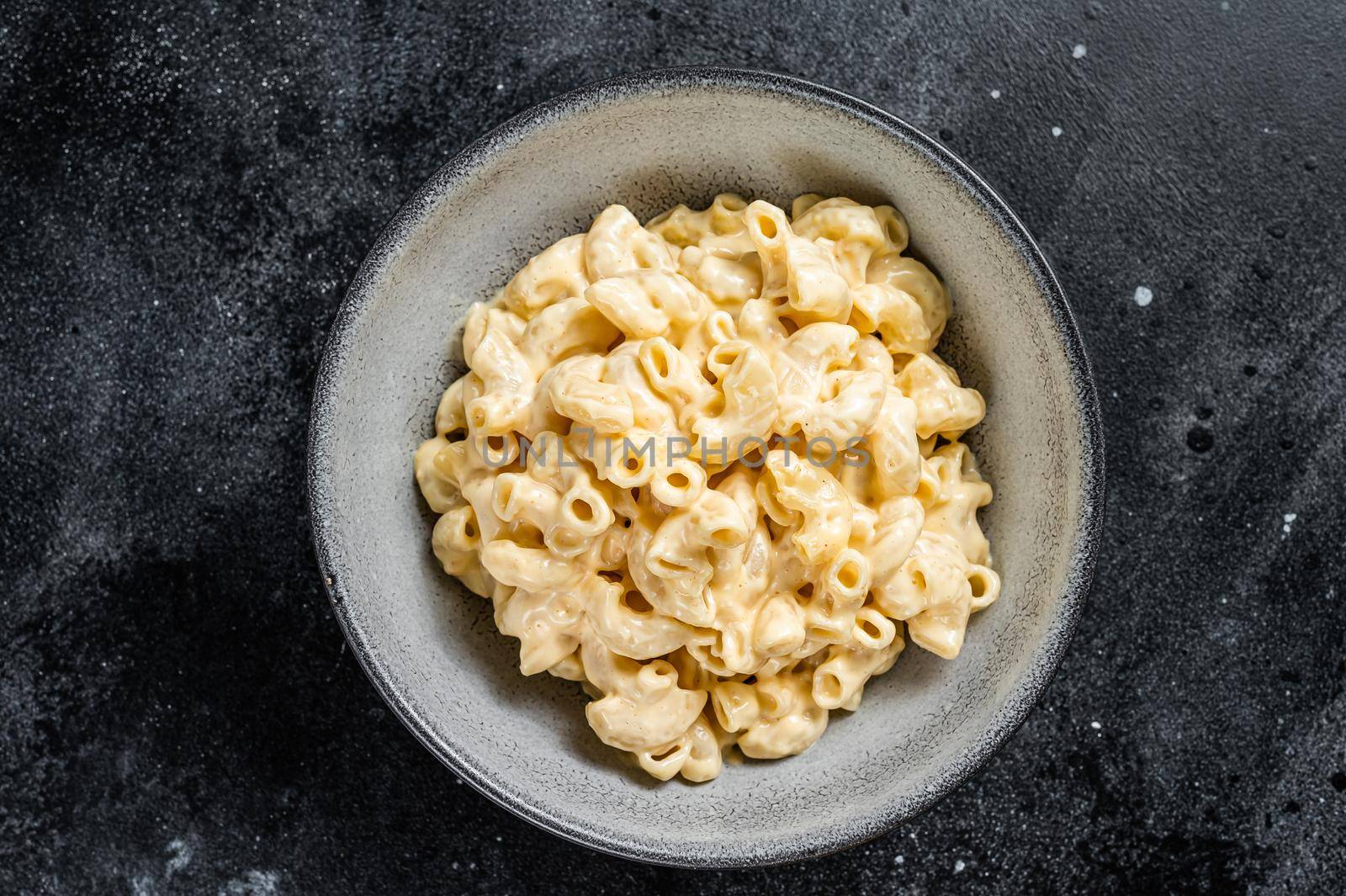 Mac and cheese american macaroni pasta with cheesy Cheddar sauce. Black background. Top view by Composter