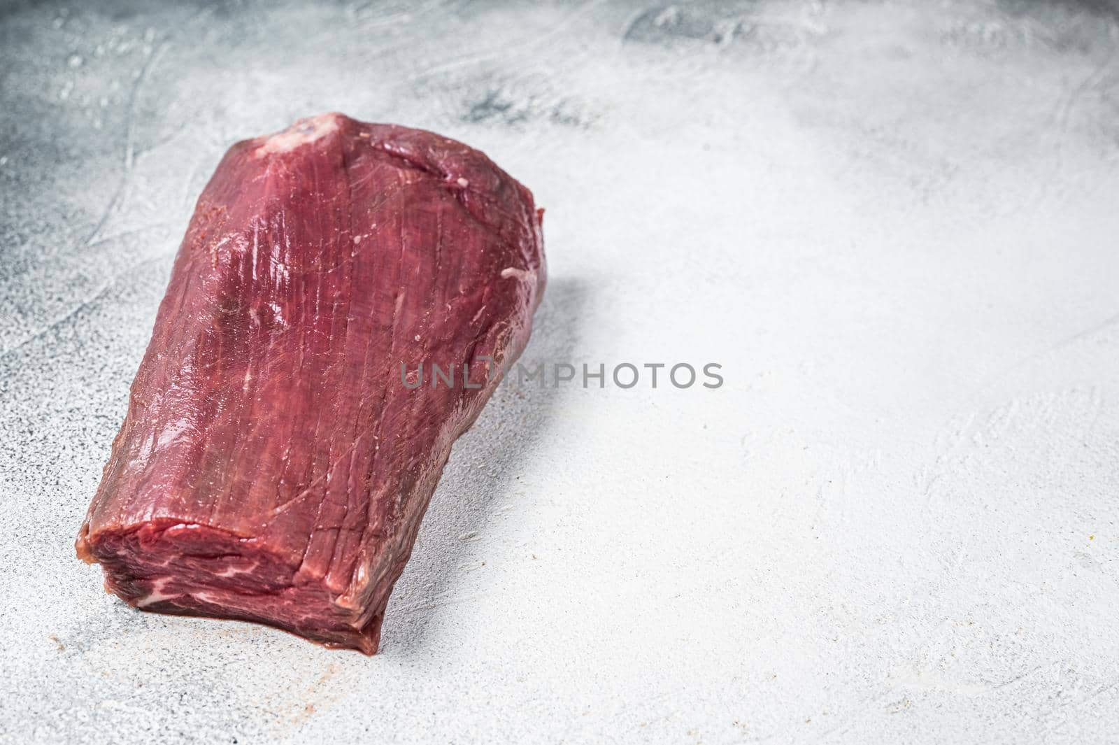 Beef Tenderloin raw meat on butcher table. White background. Top view. Copy space.
