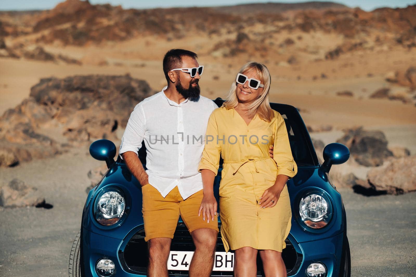 a woman and a man wearing glasses in a convertible car on a trip to the island of Tenerife. The crater of the Teide volcano, Canary Islands,Spain.