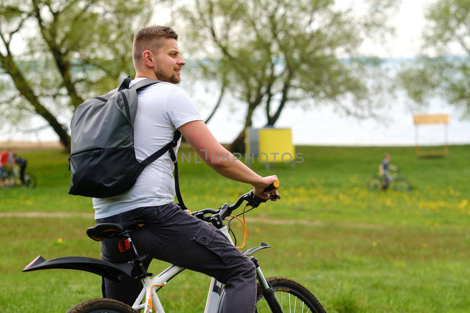 A cyclist with a backpack is standing on a bicycle in a clearing enjoying nature.