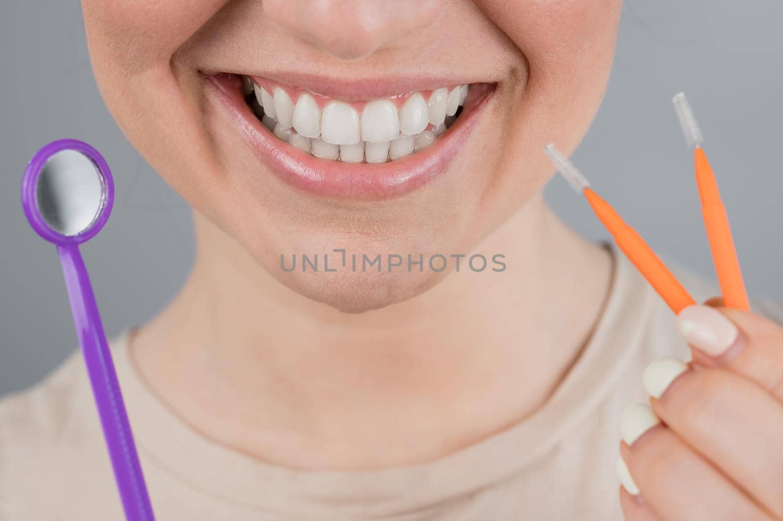 Close-up portrait of a smiling woman holding a brush and a dental mirror. Widescreen.