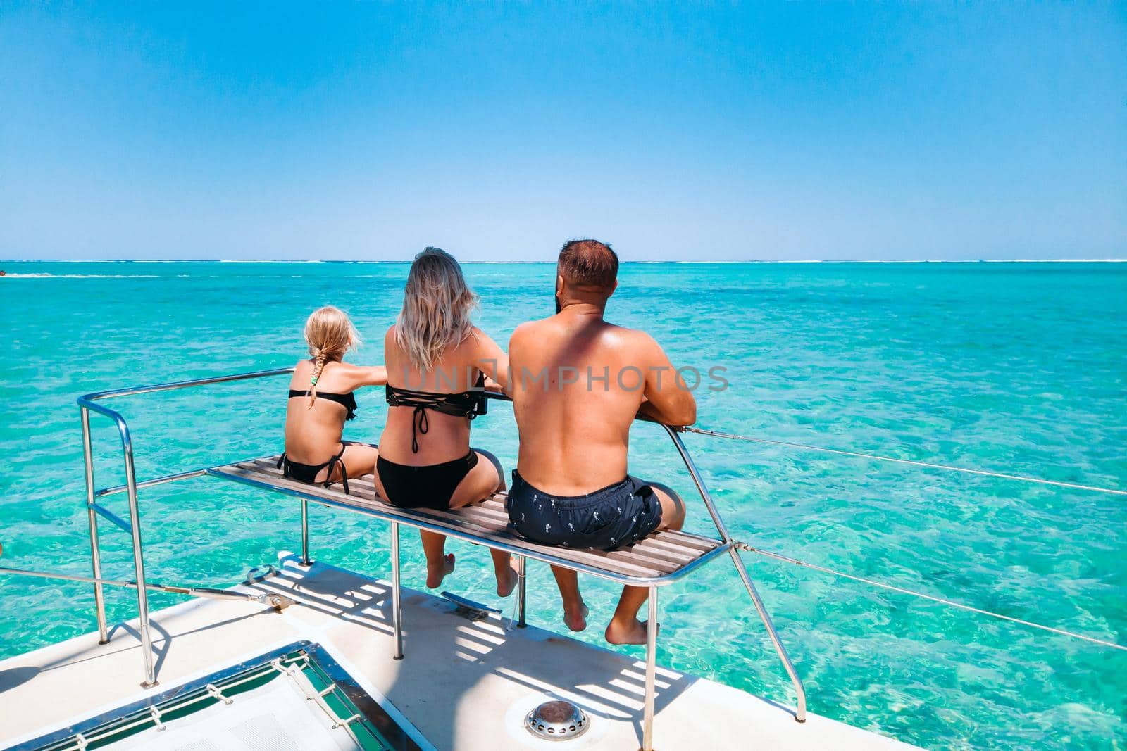 A young beautiful family with a child looks sitting on a yacht at the coral reef of the island of Mauritius.Travel and recreation on the island of Mauritius.