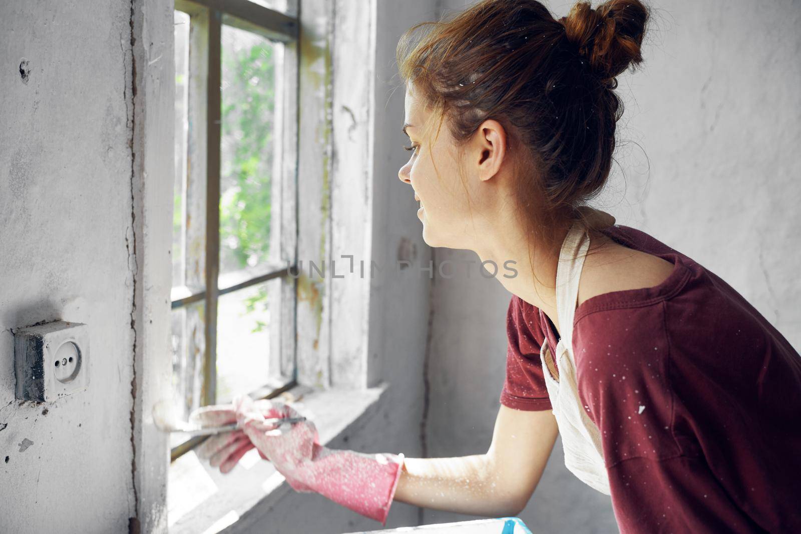 woman painter makes home repairs near window interior. High quality photo