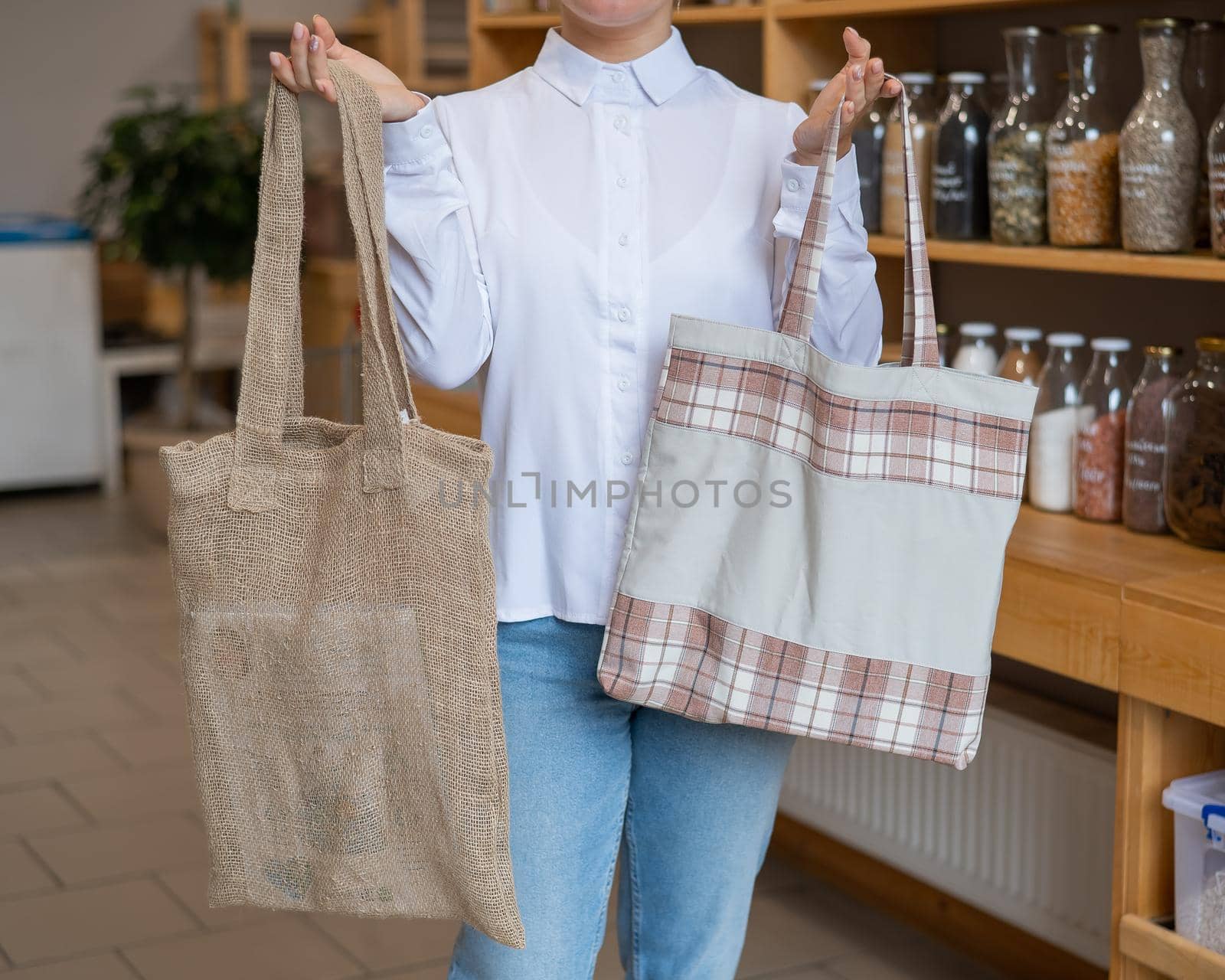 Woman choosing cotton bag at eco-friendly store by mrwed54