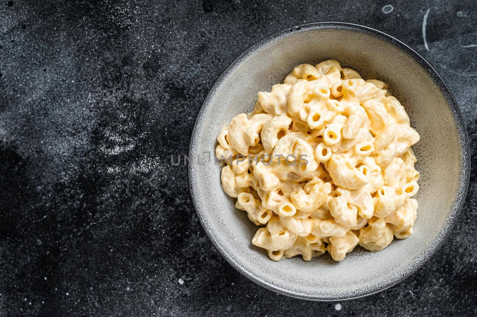 Mac and cheese american macaroni pasta with cheesy Cheddar sauce. Black background. Top view. Copy space by Composter