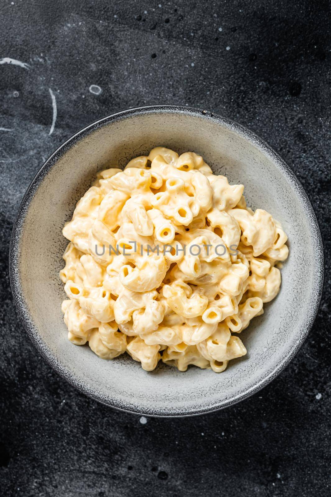 Mac and cheese american macaroni pasta with cheesy Cheddar sauce. Black background. Top view.