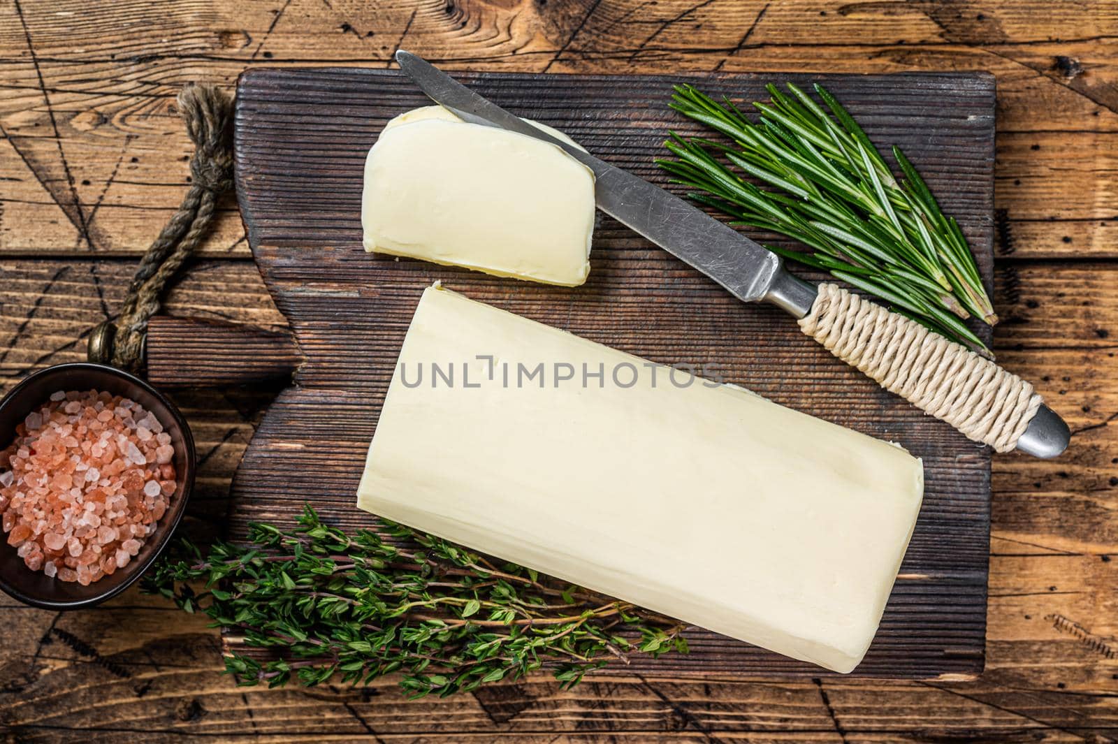 Butter sliced Spread block on a wooden board with herbs. wooden background. Top view by Composter