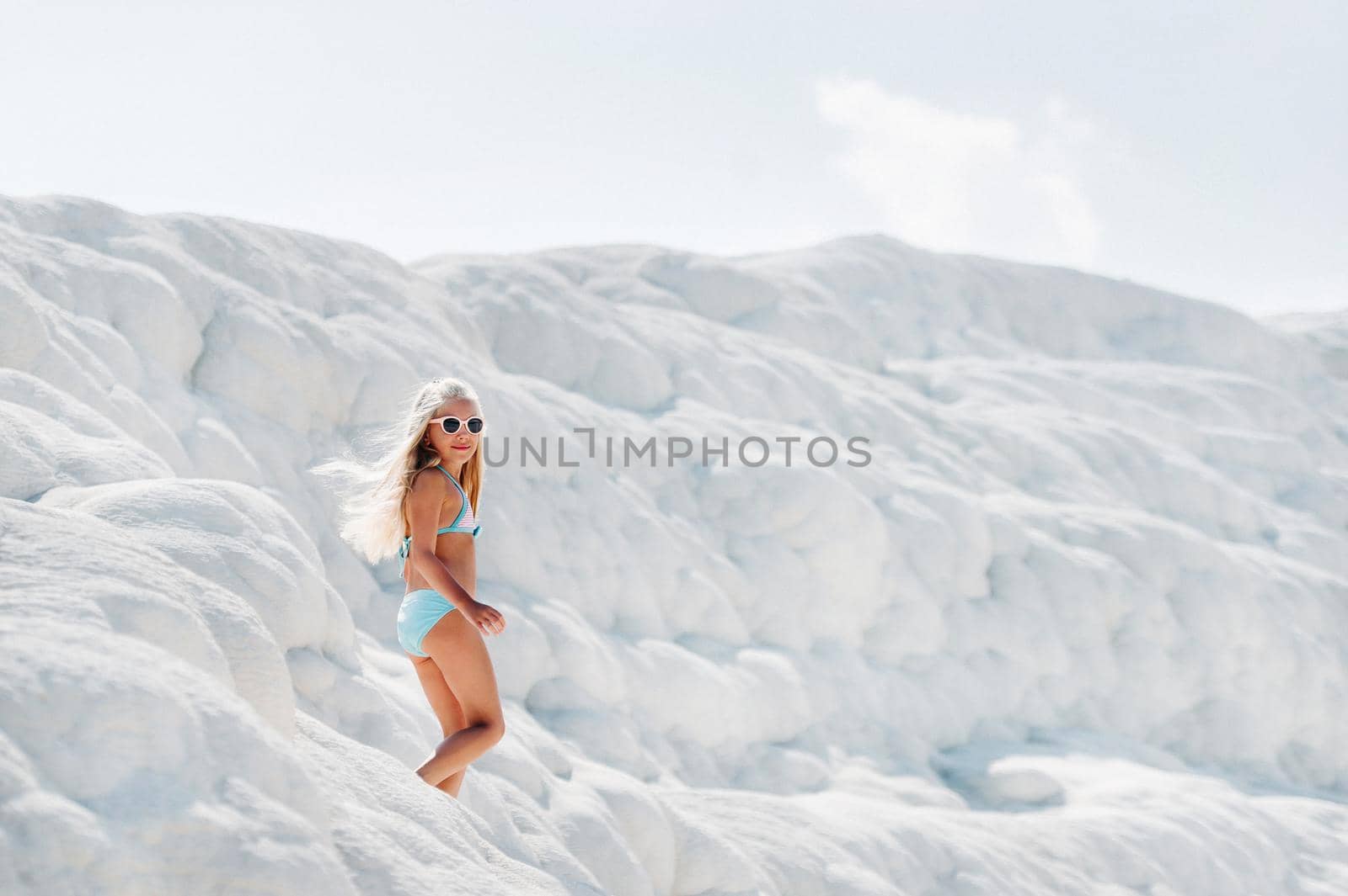 Girl in a swimsuit and sunglasses on White mountain, Sunny day, Pamukkale Turkey.