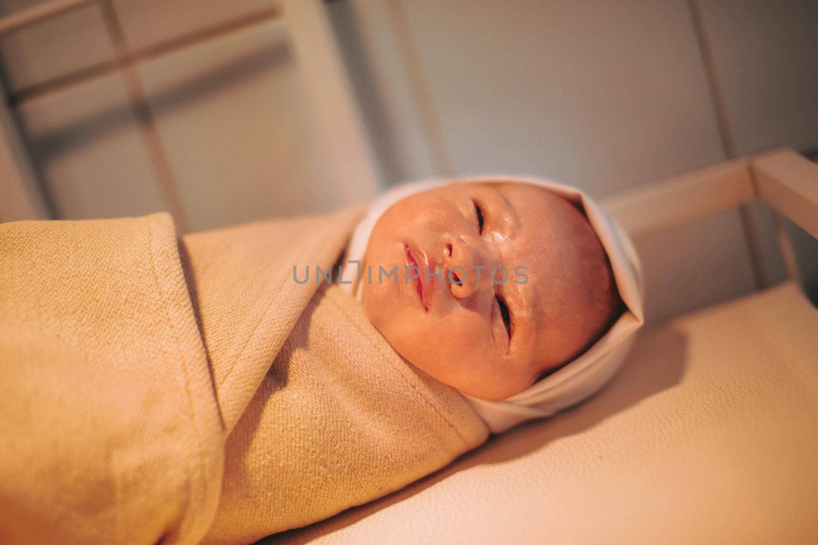 A newborn baby wrapped up after birth lies on the table.