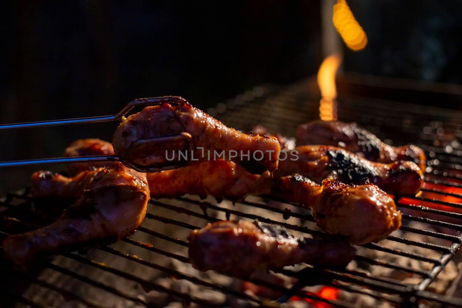 chicken drumsticks are grilled on a barbecue grill by Mariaprovector