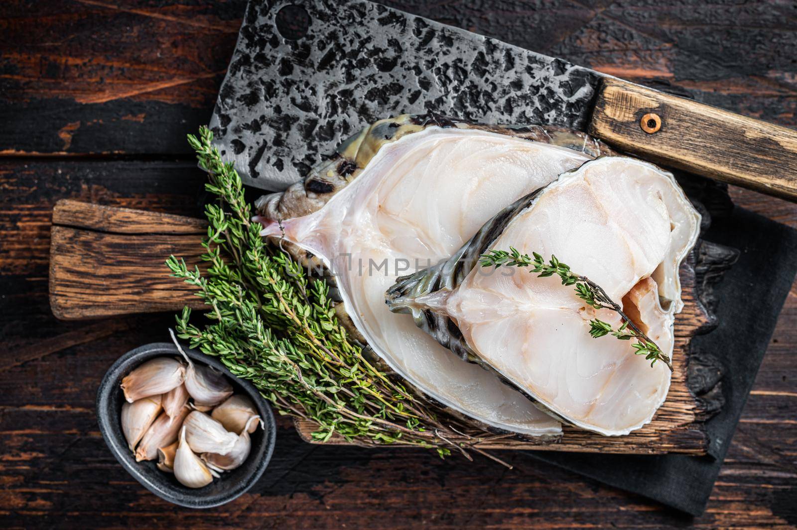 Fresh Raw wolffish o wolf fish Steak on a butcher board. Dark wooden background. Top view.