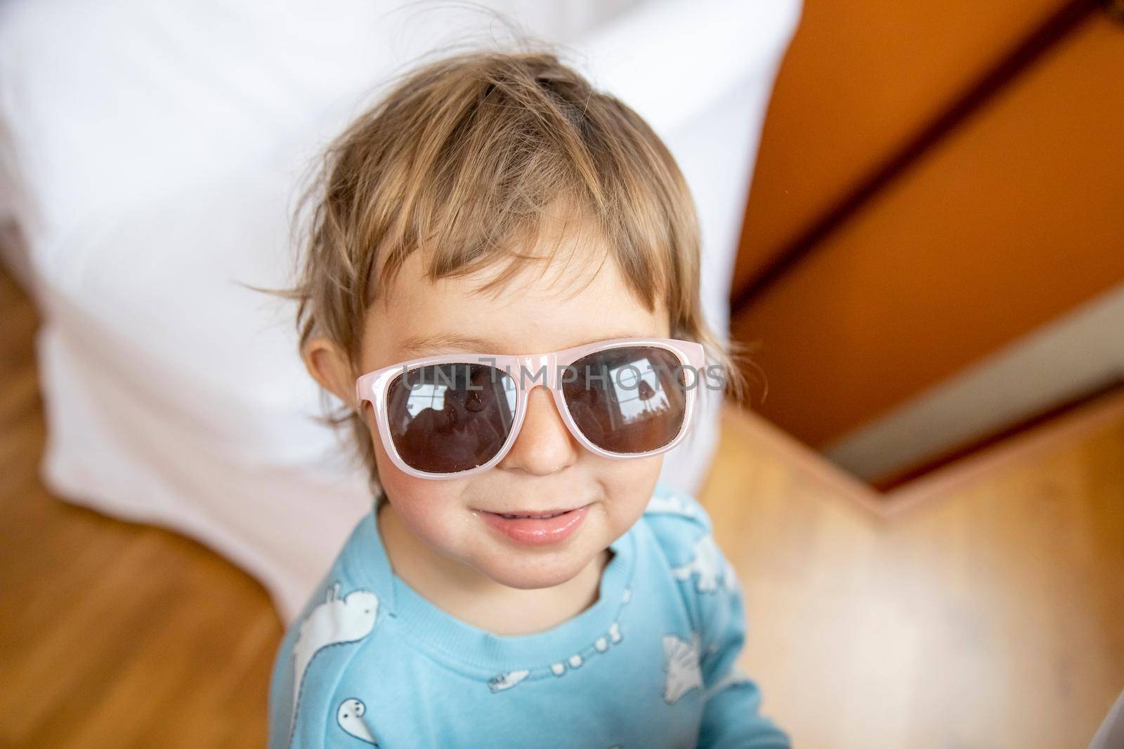 portrait of happy smiling adorable toddler in baby sunglasses. cheerful child playing by Mariaprovector