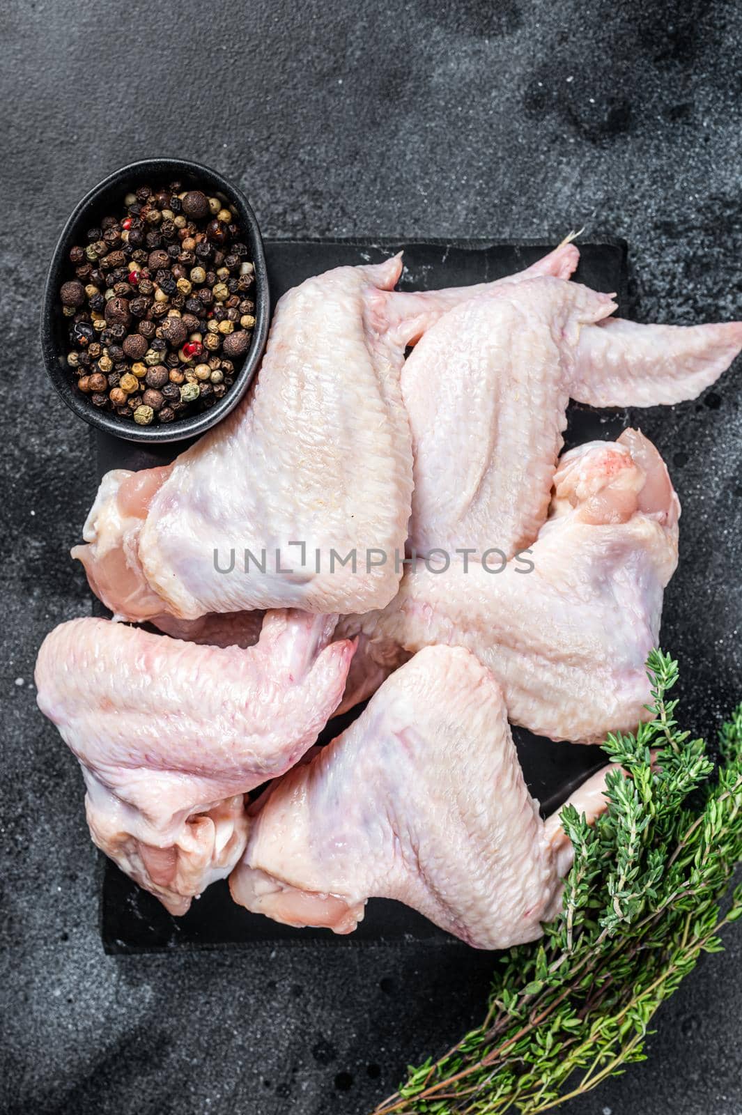 Raw chicken wings Poultry meat on a marble board. Black background. Top view by Composter