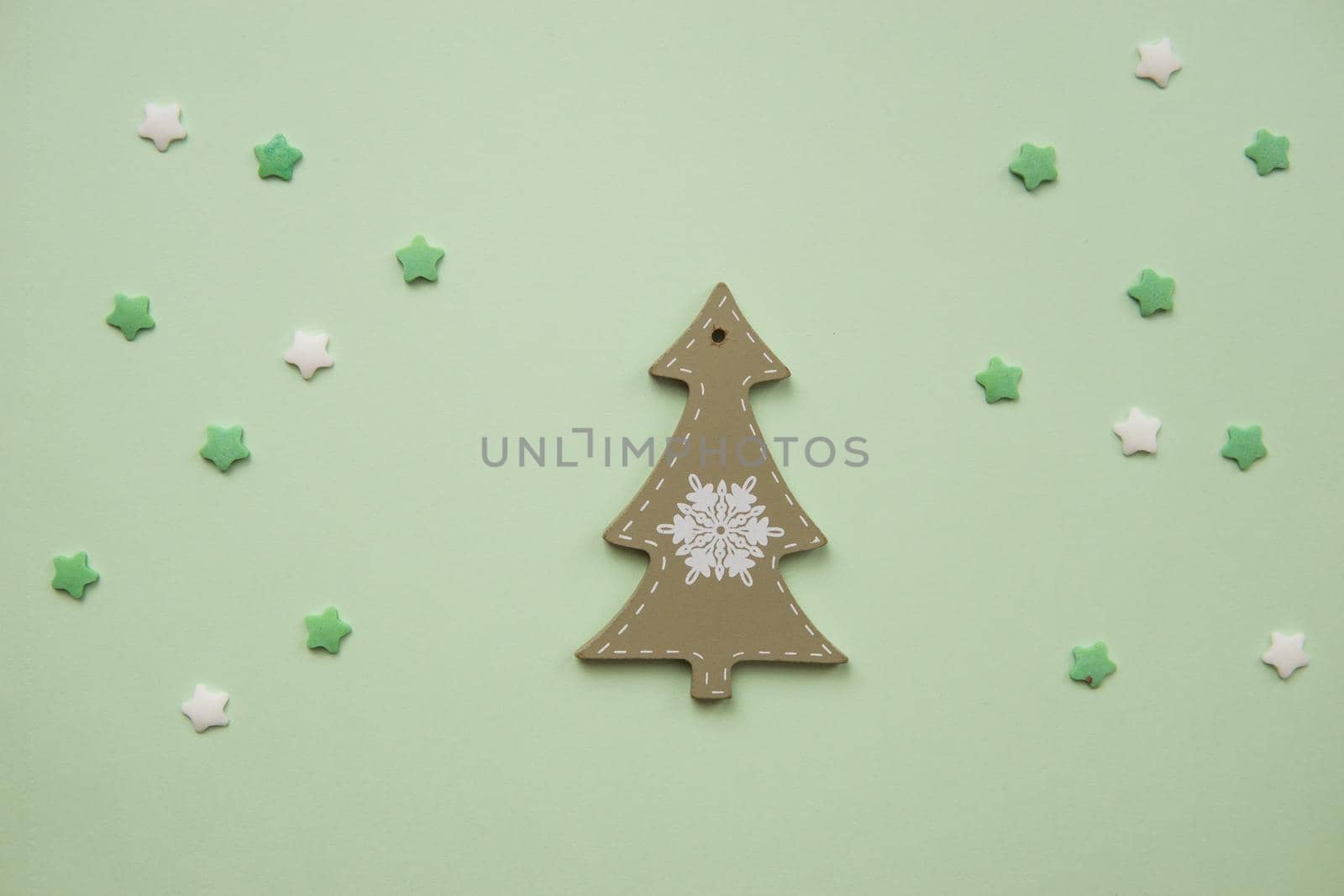 Christmas decorations decorative background. Decorative wooden white Christmas tree toy in the shape of a Christmas tree on a green background. Top view, minimalism, flat lay