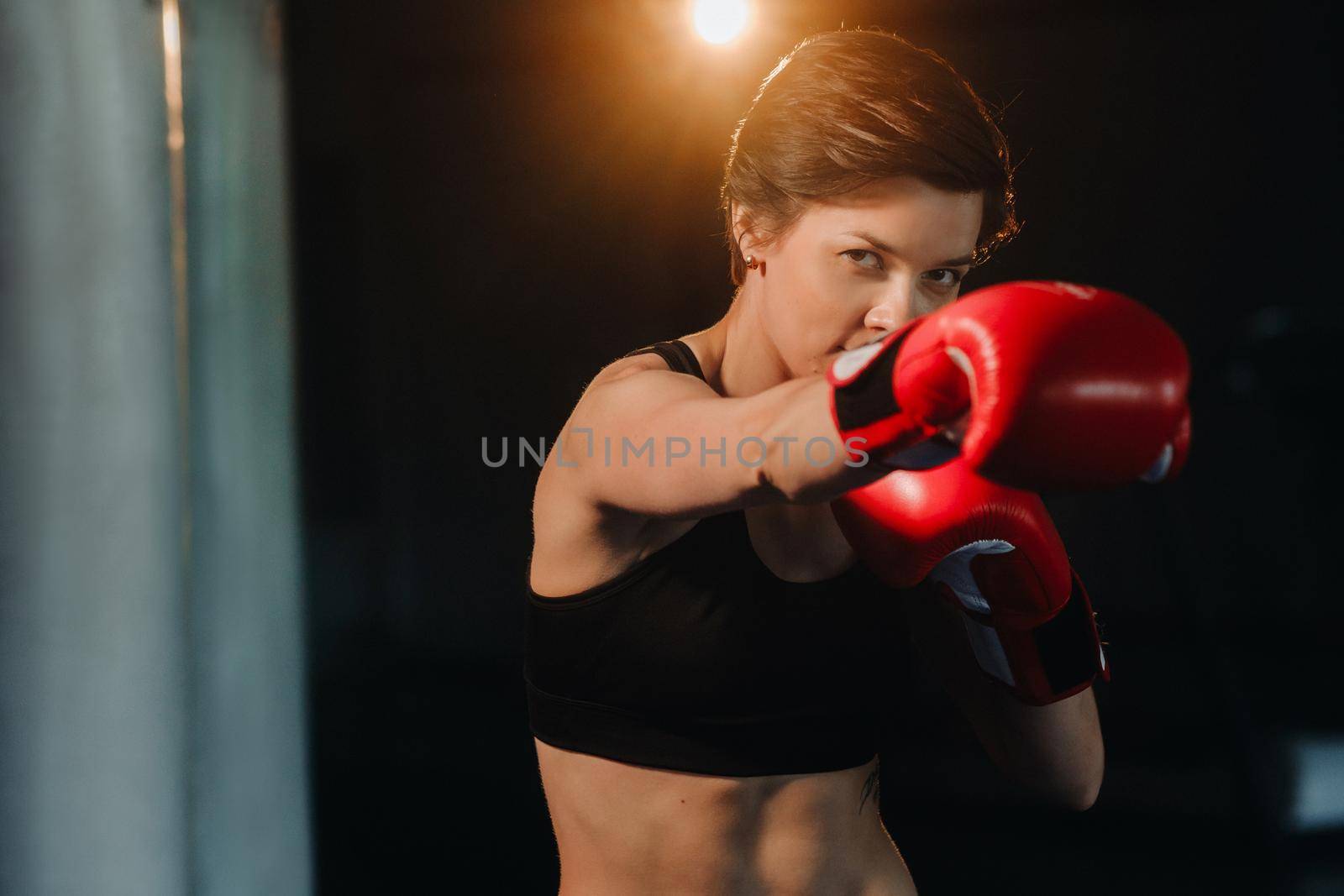 portrait of a female boxer in red gloves in the gym during training.