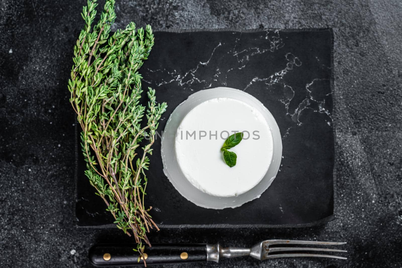 Ricotta cream Cheese on marble board with thyme. Black background. Top view by Composter