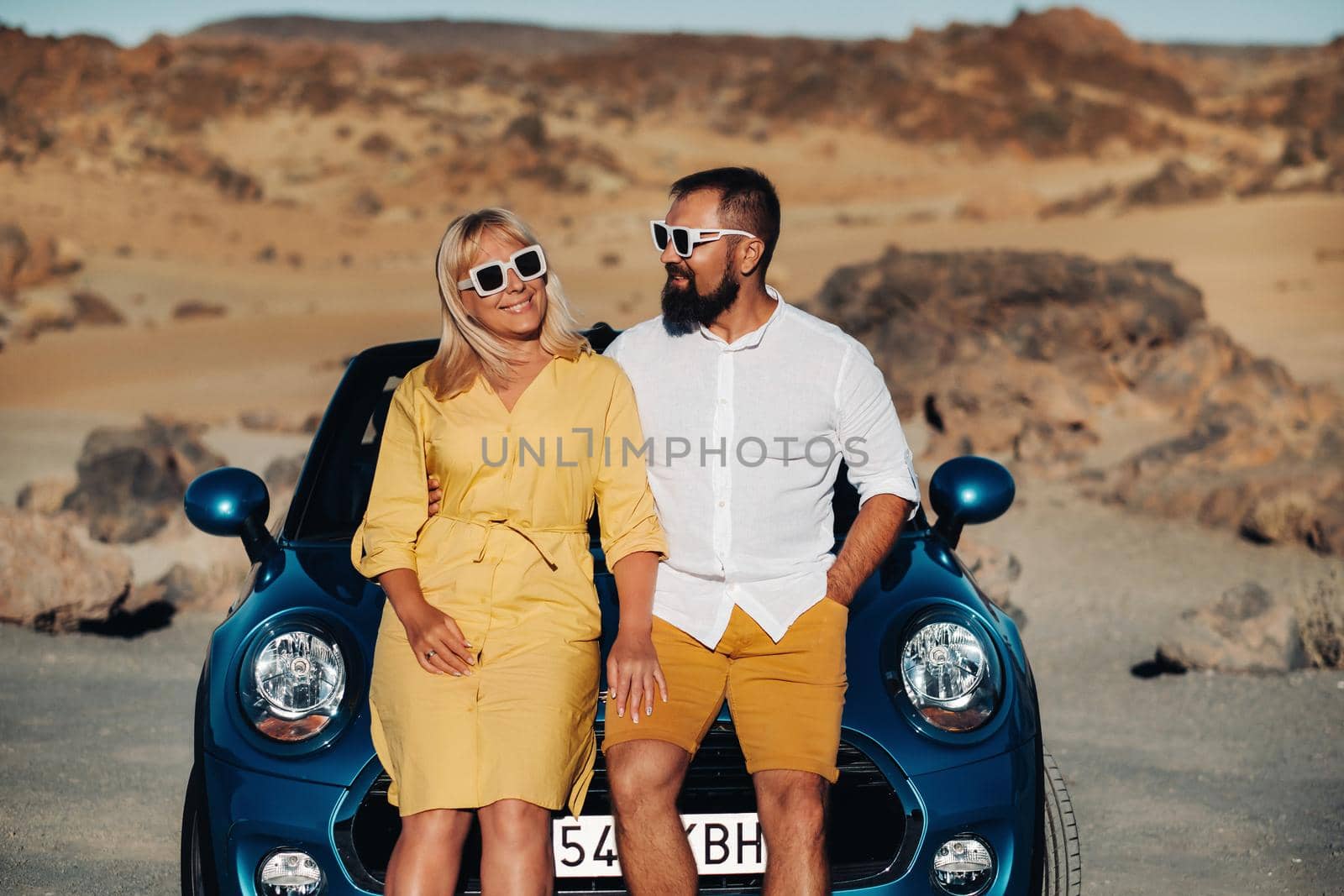 a woman and a man wearing glasses in a convertible car on a trip to the island of Tenerife. The crater of the Teide volcano, Canary Islands,Spain.