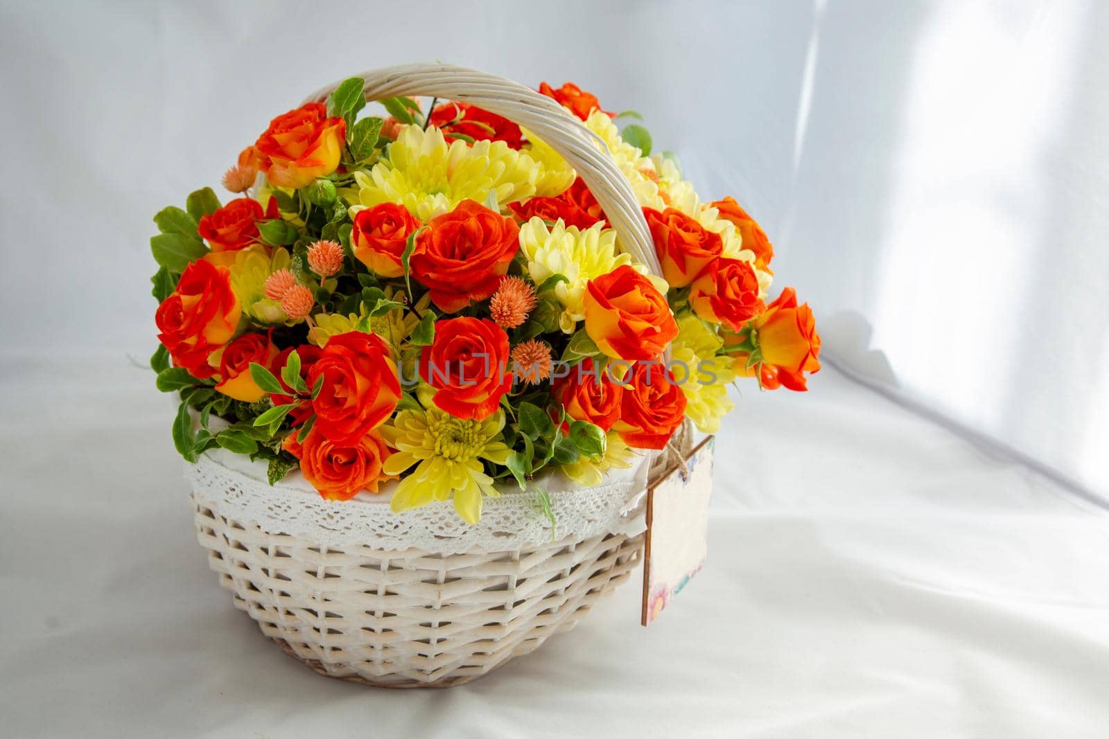 Flowers bunch wicker basket, with red roses and yellow chrysanthemums in gift box. close up, white background