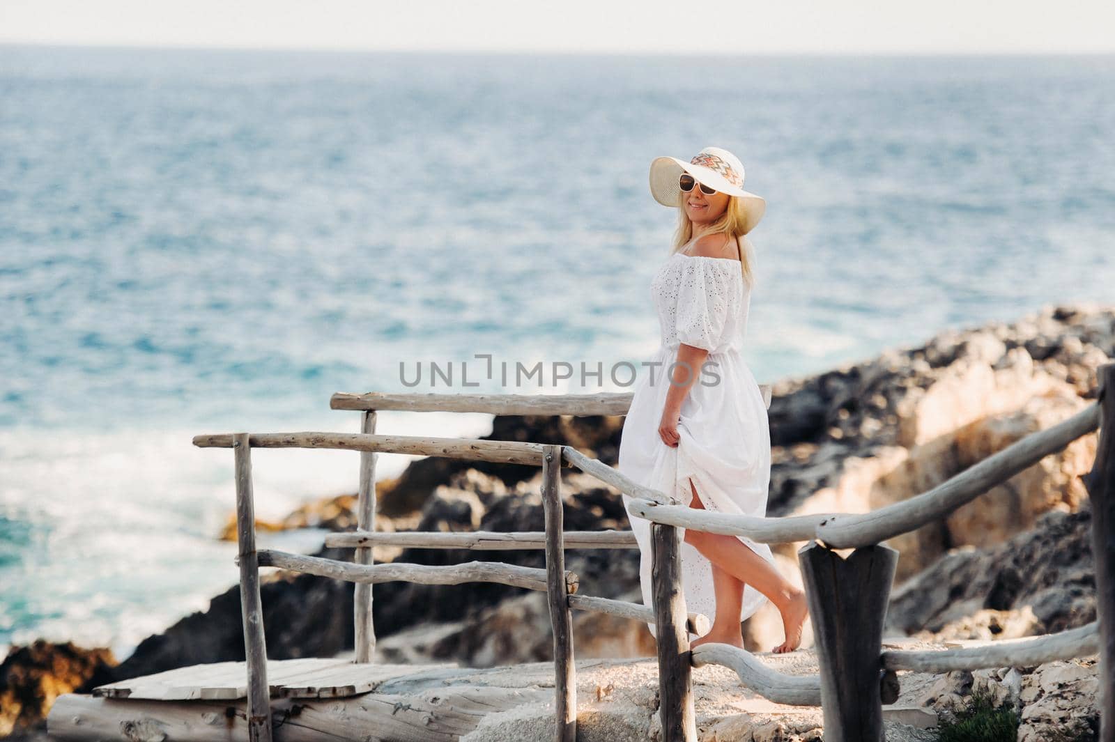 Smiling Beautiful Woman on the Beach In a Straw Hat on the island of Zakynthos.A girl in a white dress at sunset on Zakynthos island, Greece