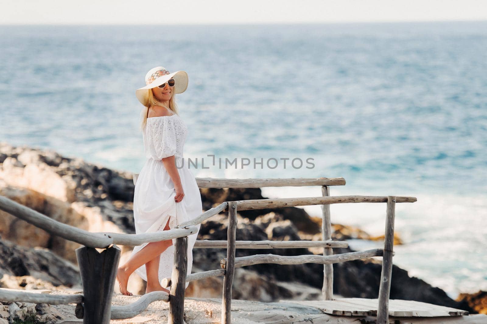 Smiling Beautiful Woman on the Beach In a Straw Hat on the island of Zakynthos.A girl in a white dress at sunset on Zakynthos island, Greece.